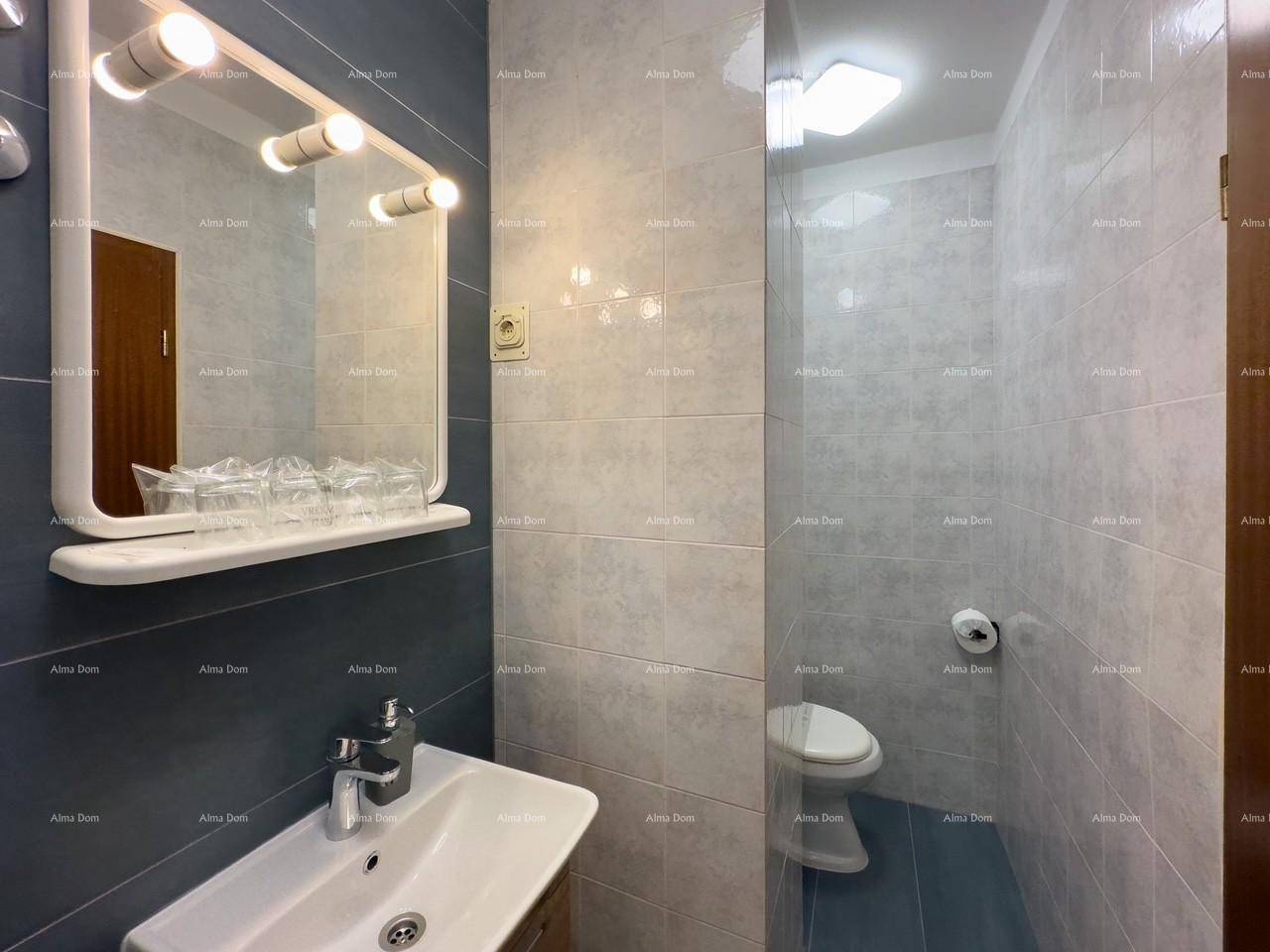 Badezimmer mit Waschbecken und WC, ausgestattet mit grauen Fliesen und einem Spiegel.