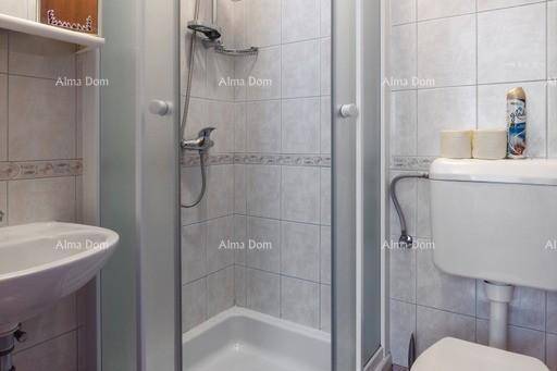 Kleines Badezimmer mit Duschkabine, WC und Waschbecken, ausgestattet mit hellen Fliesen.