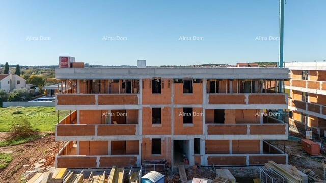 Neubau im Rohbau mit Ziegelwänden und Betondecken unter blauem Himmel.