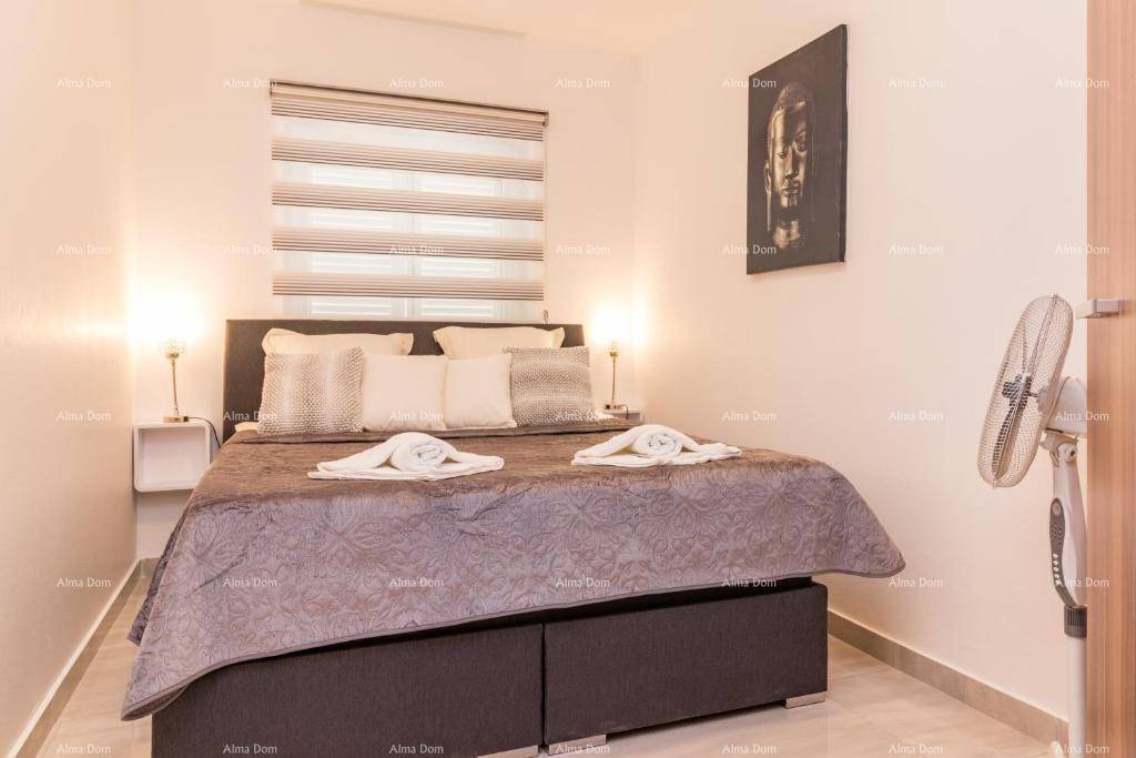 Gemütliches Schlafzimmer mit Doppelbett, Nachttischen und einem Wandventilator für angenehme Kühlung.