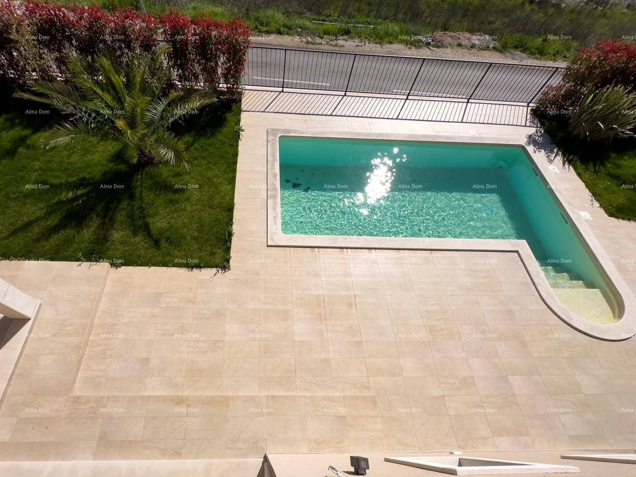 Außenbereich mit Swimmingpool, gefliester Poolumrandung und kleiner Rasenfläche.