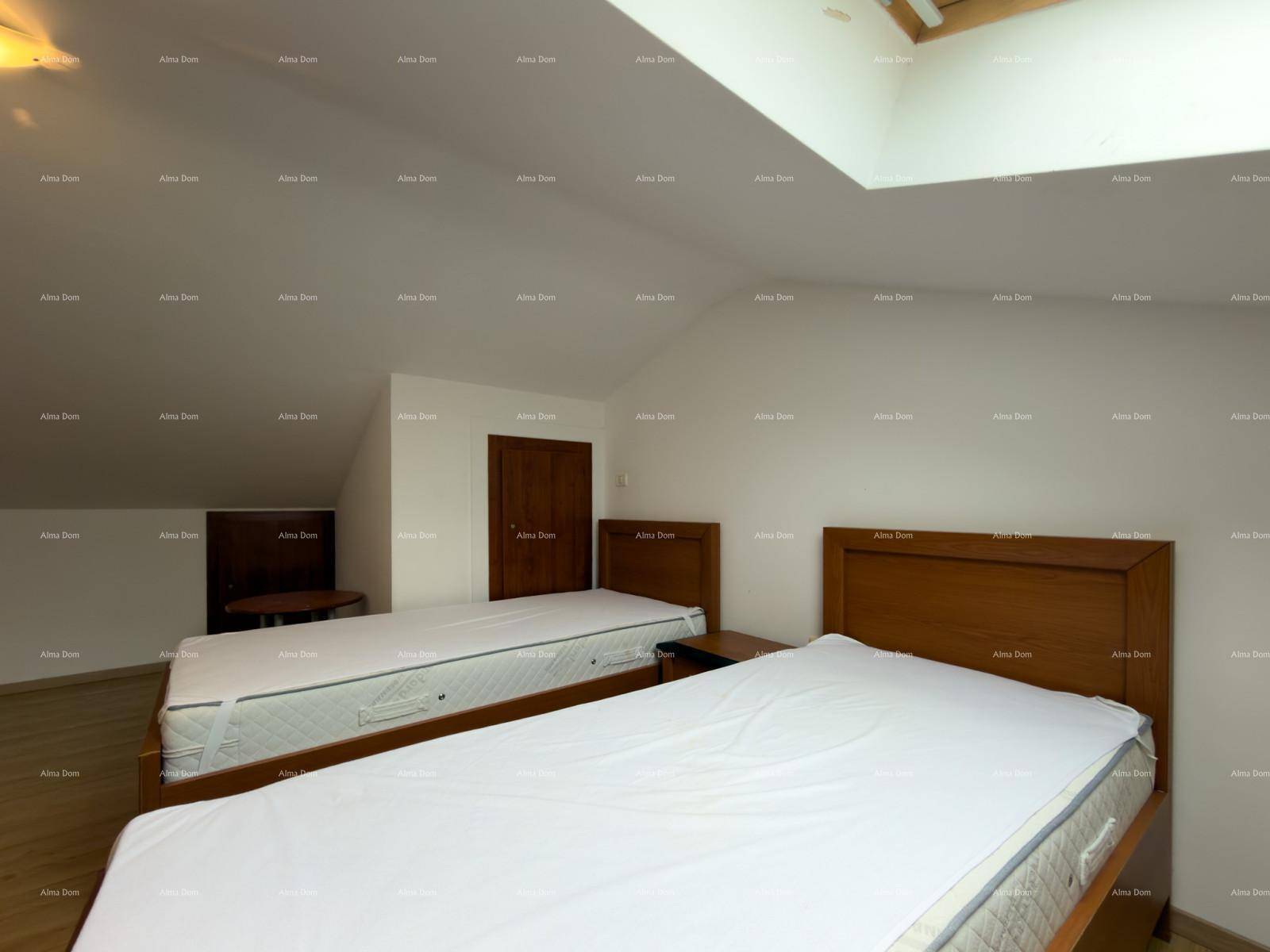 Schlafzimmer im Dachgeschoss mit zwei Betten, Holzfußboden und einer Holztür.