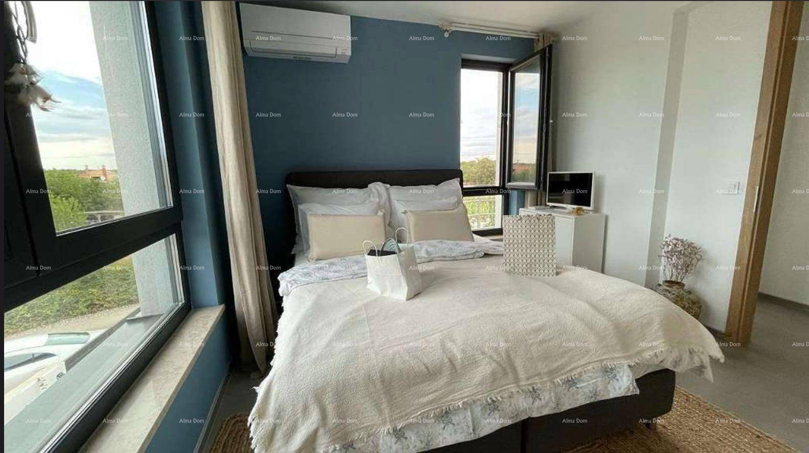 Helles Schlafzimmer mit Doppelbett, großen Fenstern und blauer Akzentwand.