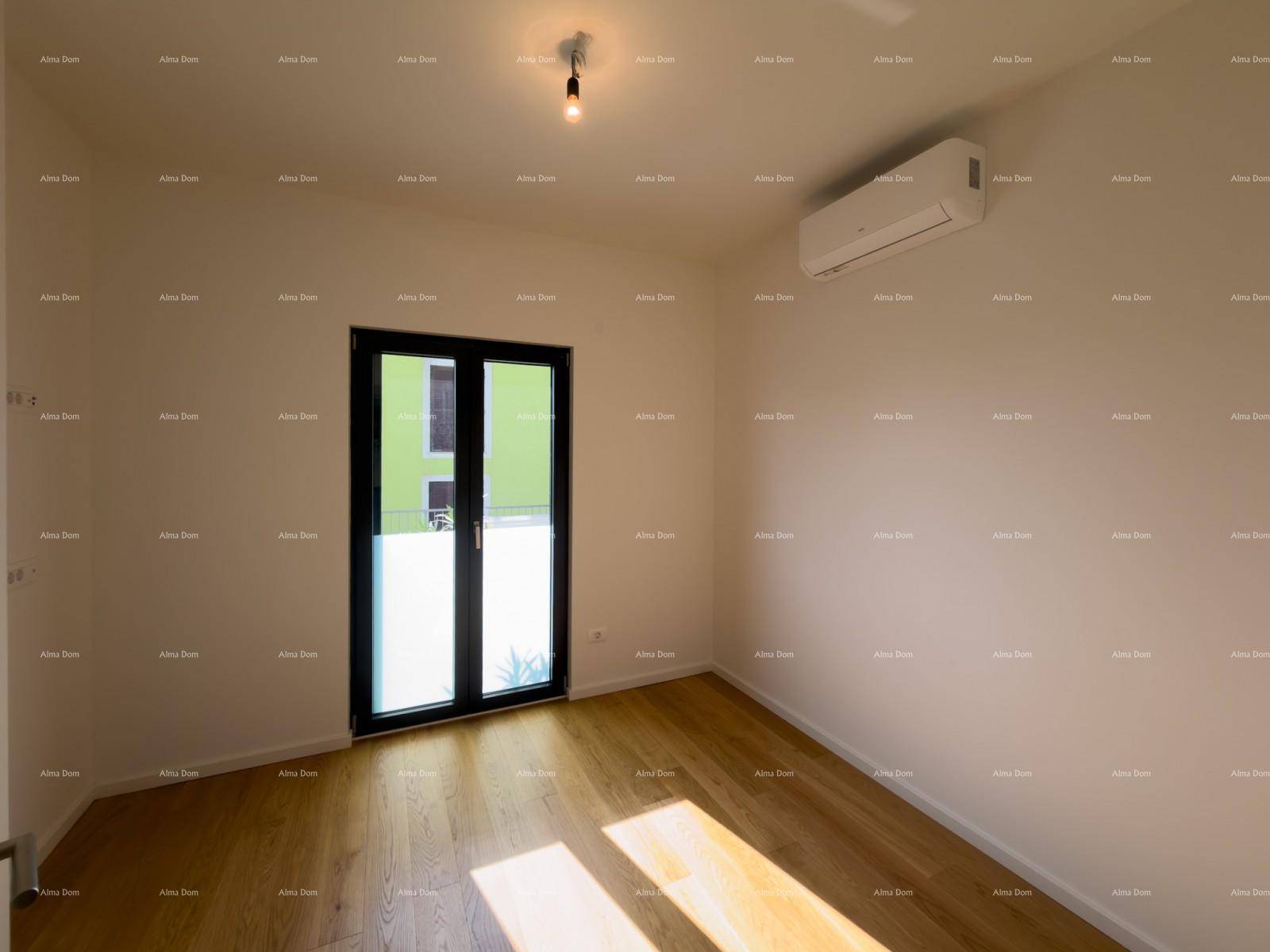 Leeres Schlafzimmer mit Holzboden, Klimaanlage und großem Fenster mit Zugang nach draußen.
