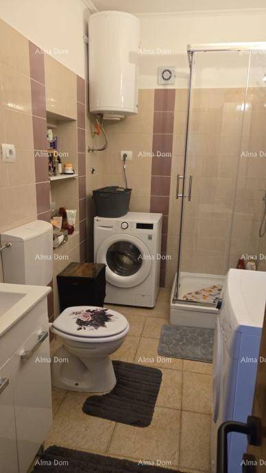 Badezimmer mit Dusche, WC, Waschmaschine und Fliesen in Beige- und Brauntönen.