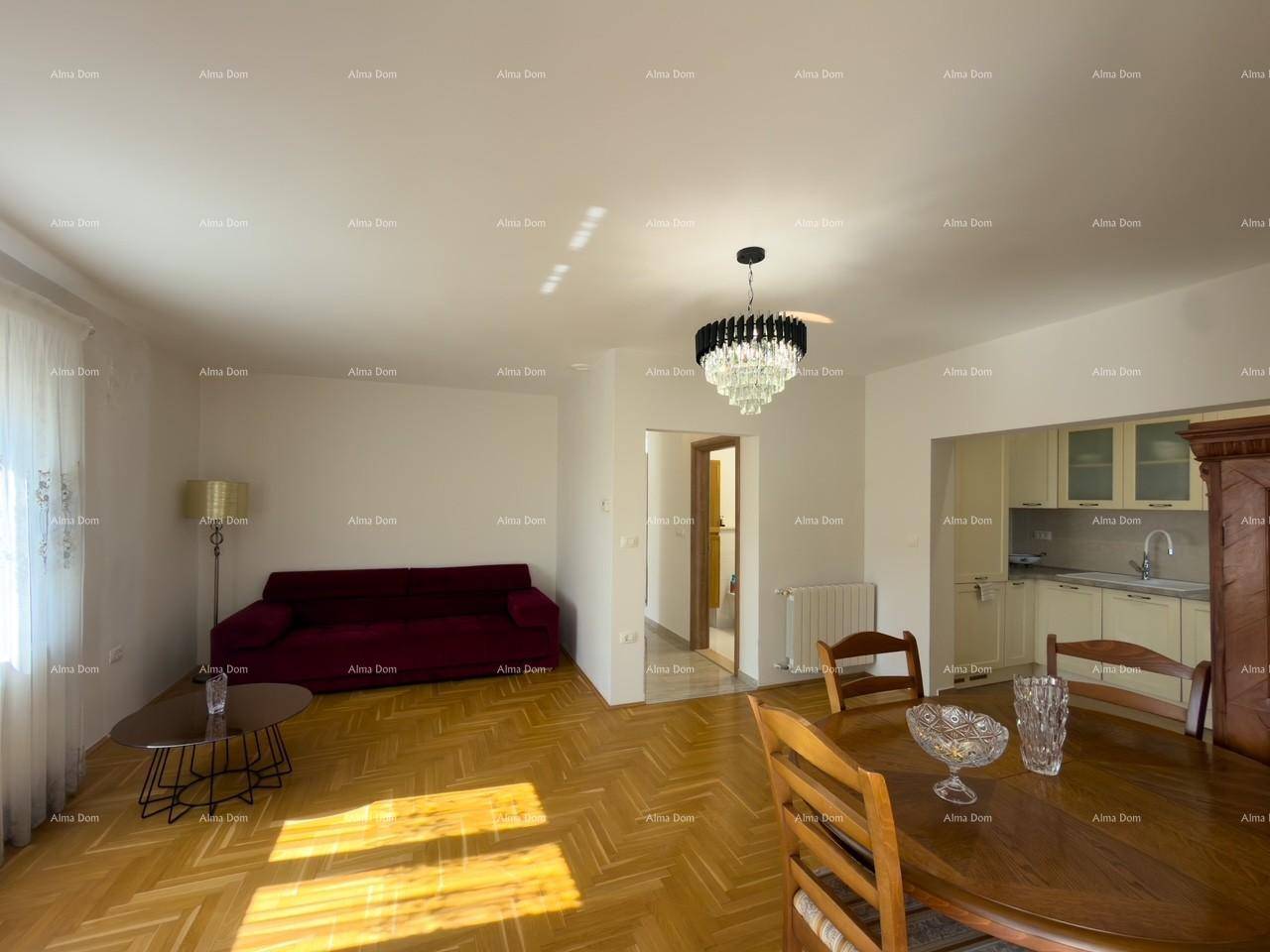 Heller Wohn- und Essbereich mit Parkettboden, rotem Sofa und Kronleuchter.