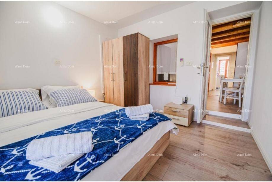 Helles Schlafzimmer mit Holzboden, Doppelbett und Zugang zu einem weiteren Raum.