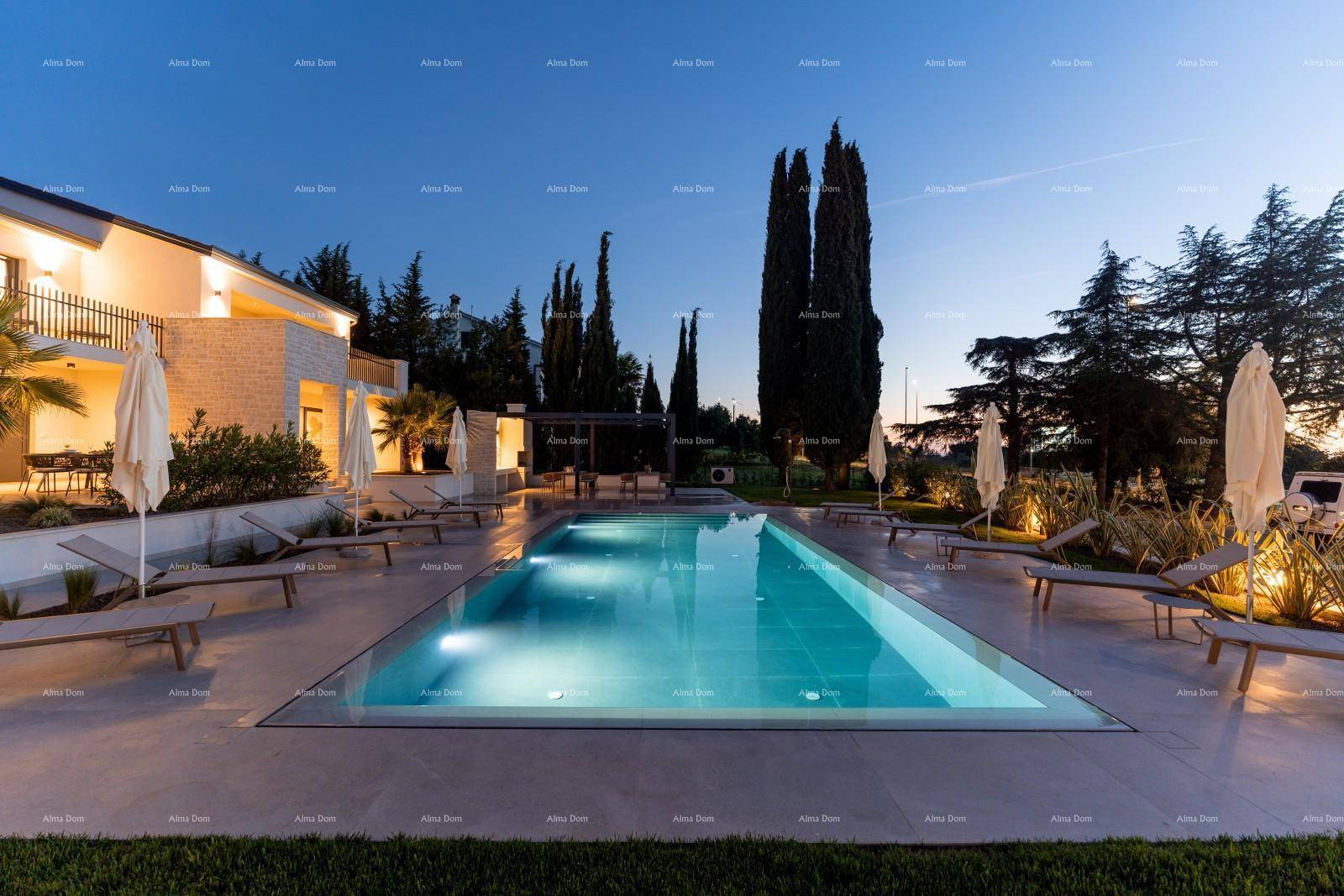 Luxuriöser Außenbereich der Villa bei Dämmerung mit beleuchtetem Pool und hohen Bäumen.