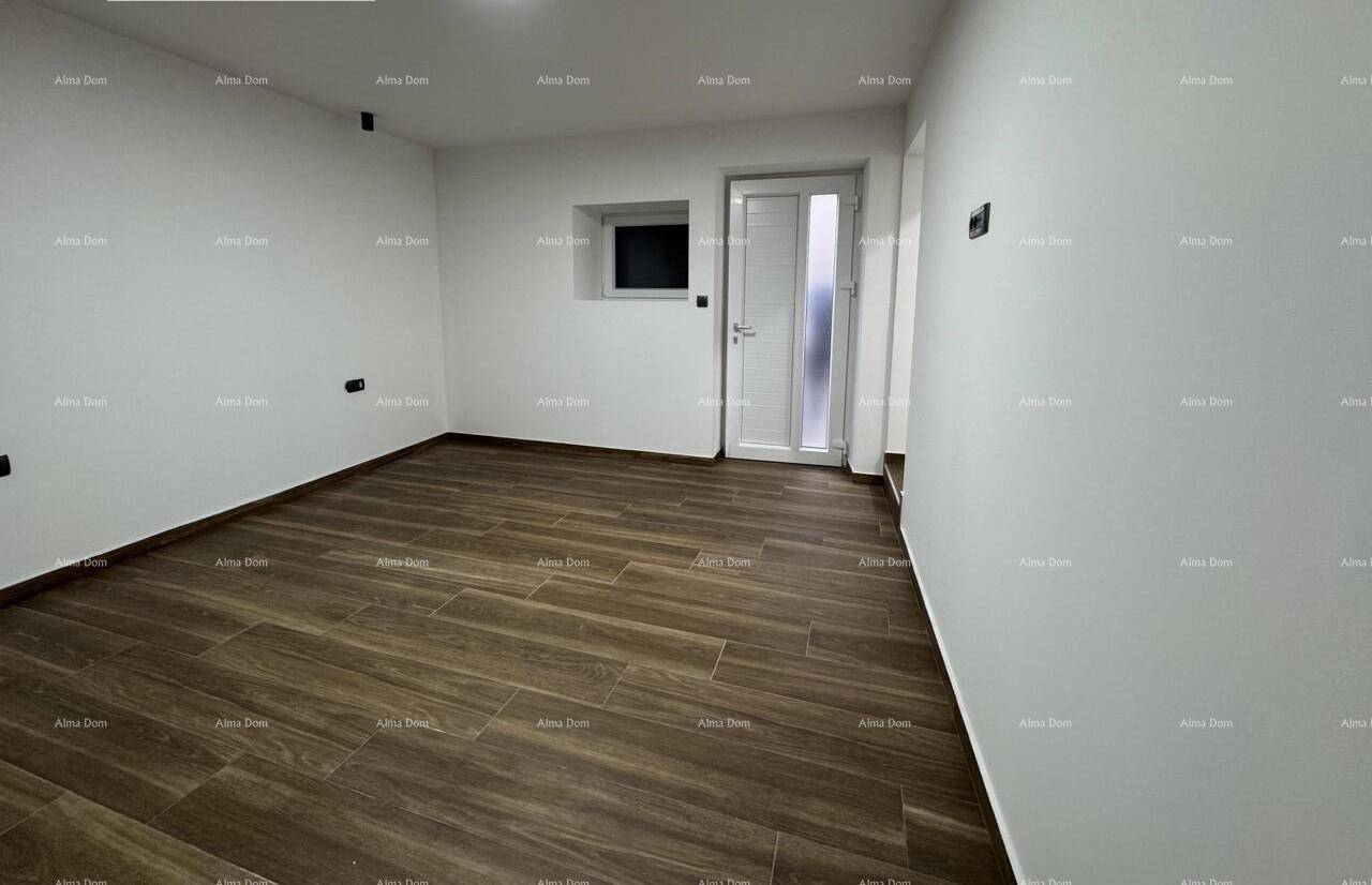 Geräumiger, leerer Raum mit Holzboden und Zugang nach draußen.