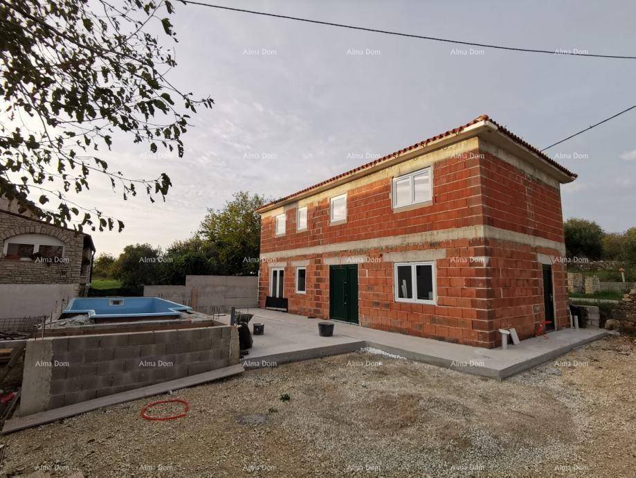 Rohbau eines Hauses mit Ziegelwänden und einem im Bau befindlichen Pool im Vordergrund.