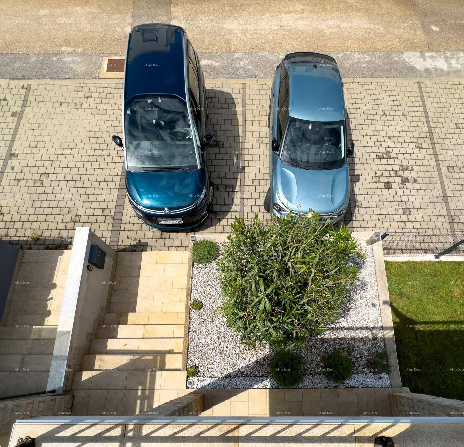 Gepflasterter Parkplatz mit zwei Autos, umgeben von Grünflächen und einer Steintreppe.