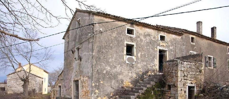 Weitläufige Außenansicht des alten Steinhauses mit kahlen Bäumen und einem weiteren Gebäude in der Ferne.
