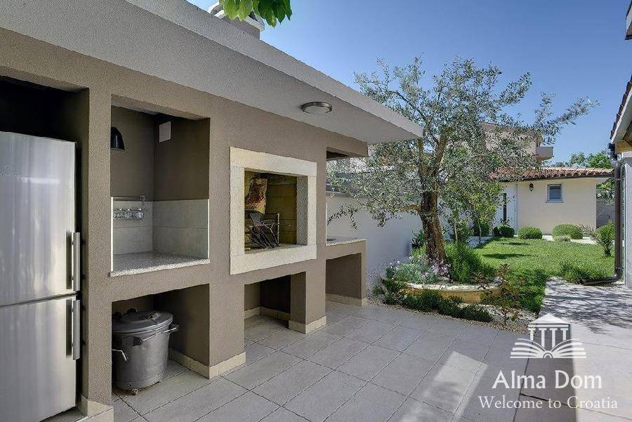 Moderne Außenküche mit Grillbereich und Kühlschrank, ideal für gesellige Abende im Freien.
