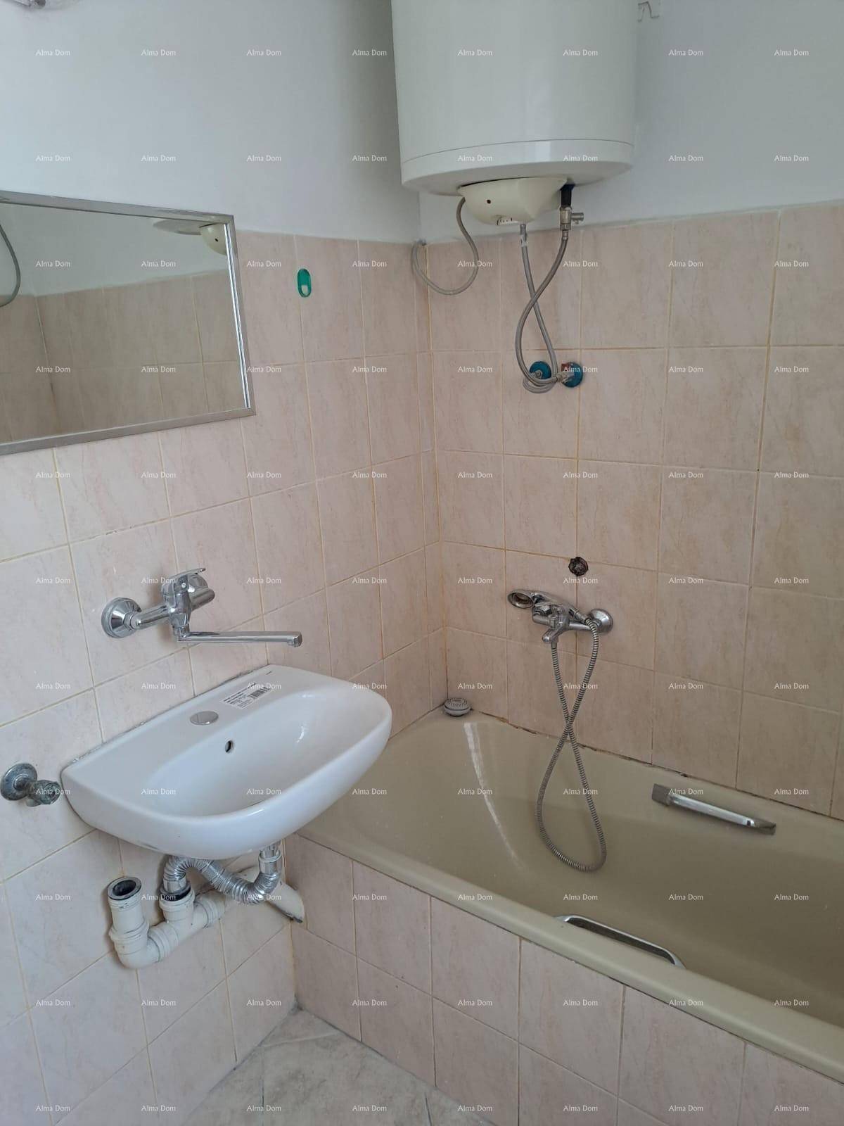 Badezimmer mit Badewanne, Waschbecken und Warmwasserboiler, in gutem Zustand.