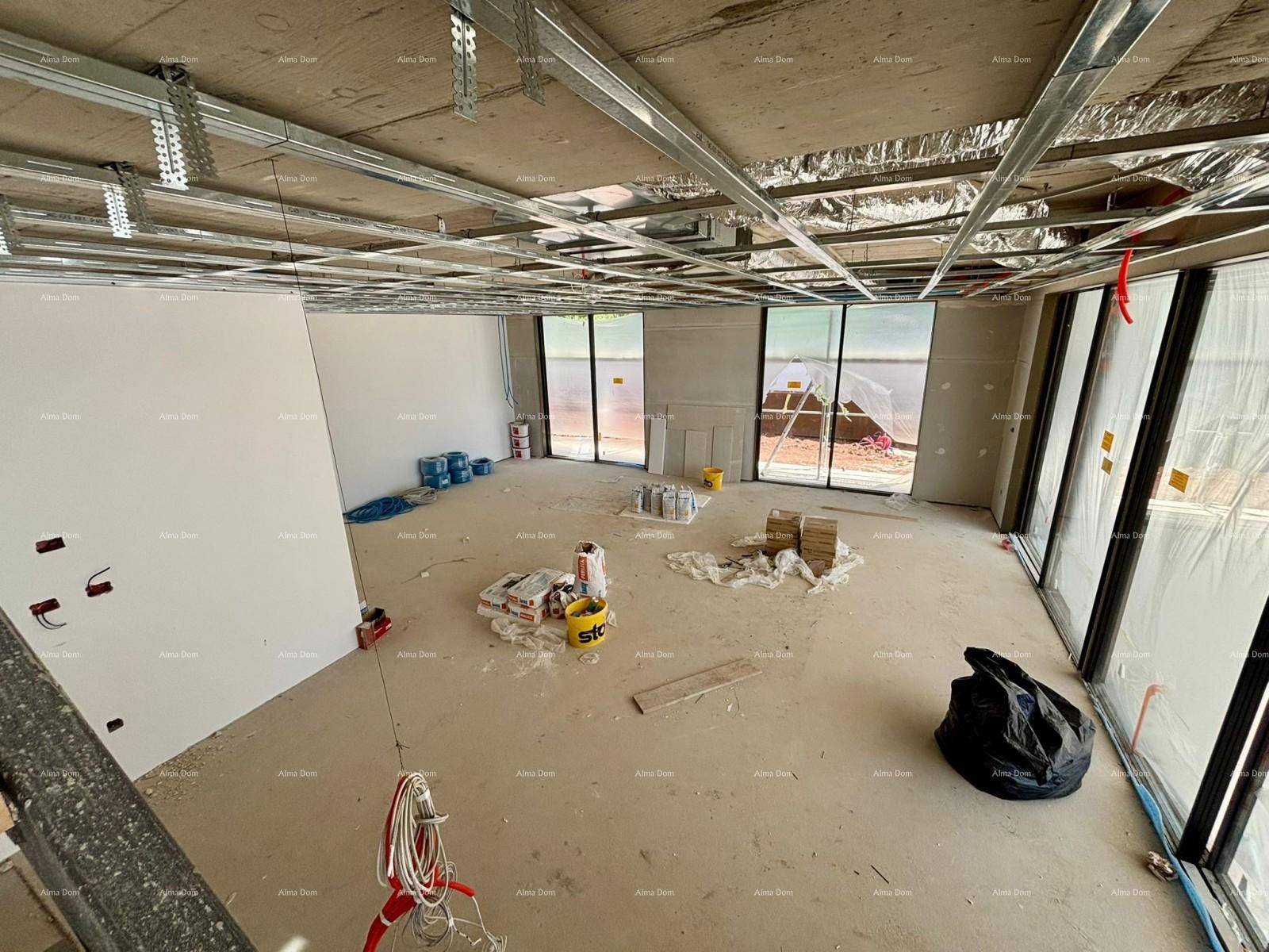 Großer offener Raum im Rohbau mit großen Fenstern und Baumaterialien für den Innenausbau.