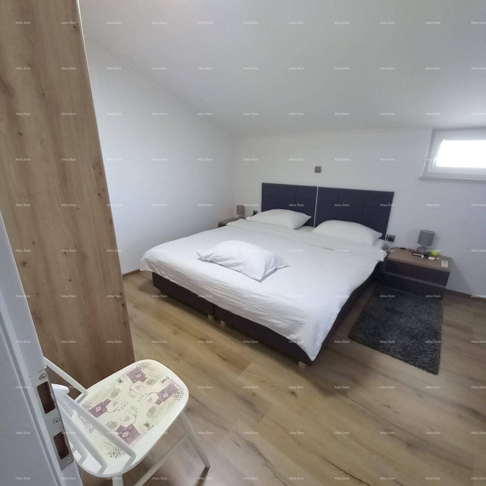 Schlafzimmer im Dachgeschoss mit Doppelbett, Dachschräge und hellem Laminatboden.