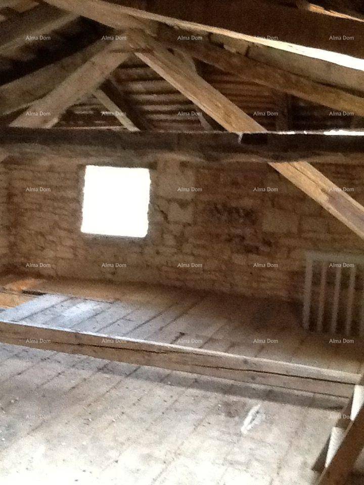 Heller Dachbodenraum mit freiliegenden Holzbalken, Steinwänden und einem kleinen Fenster.