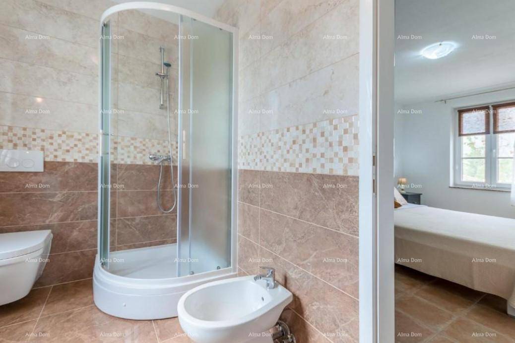 Badezimmer mit Duschkabine, Bidet und Fliesen in warmen Brauntönen, angrenzend an ein Schlafzimmer.