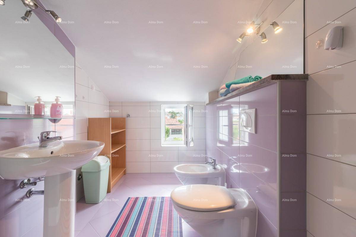 Geräumiges Badezimmer im Dachgeschoss mit lila Fliesen, Bidet, Toilette und Waschbecken.