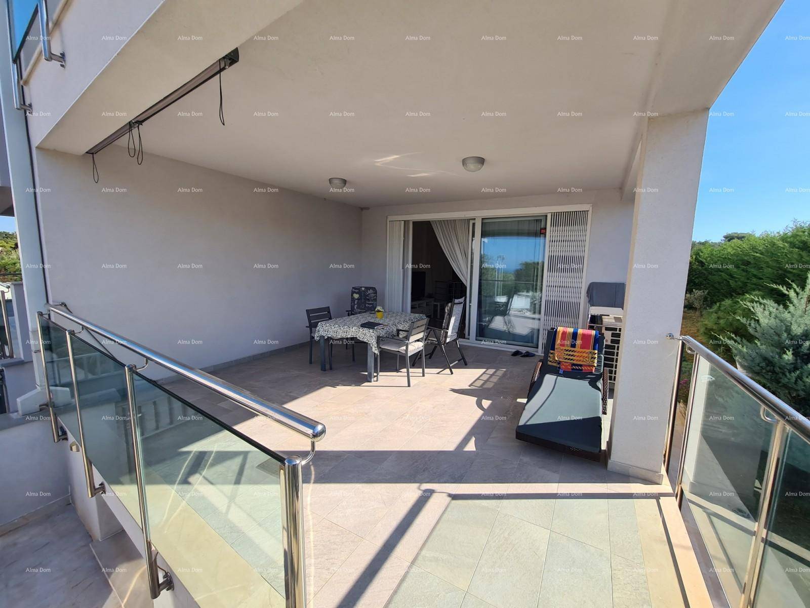 Helle Terrasse mit Glasgeländer, Sitzgelegenheiten und Blick ins Grüne.