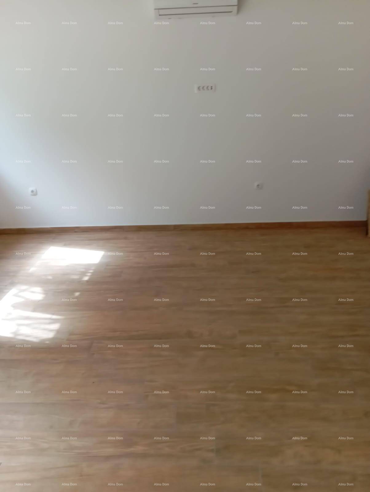Heller Wohnraum mit Holzoptik-Fliesenboden und installierter Klimaanlage an der weißen Wand.