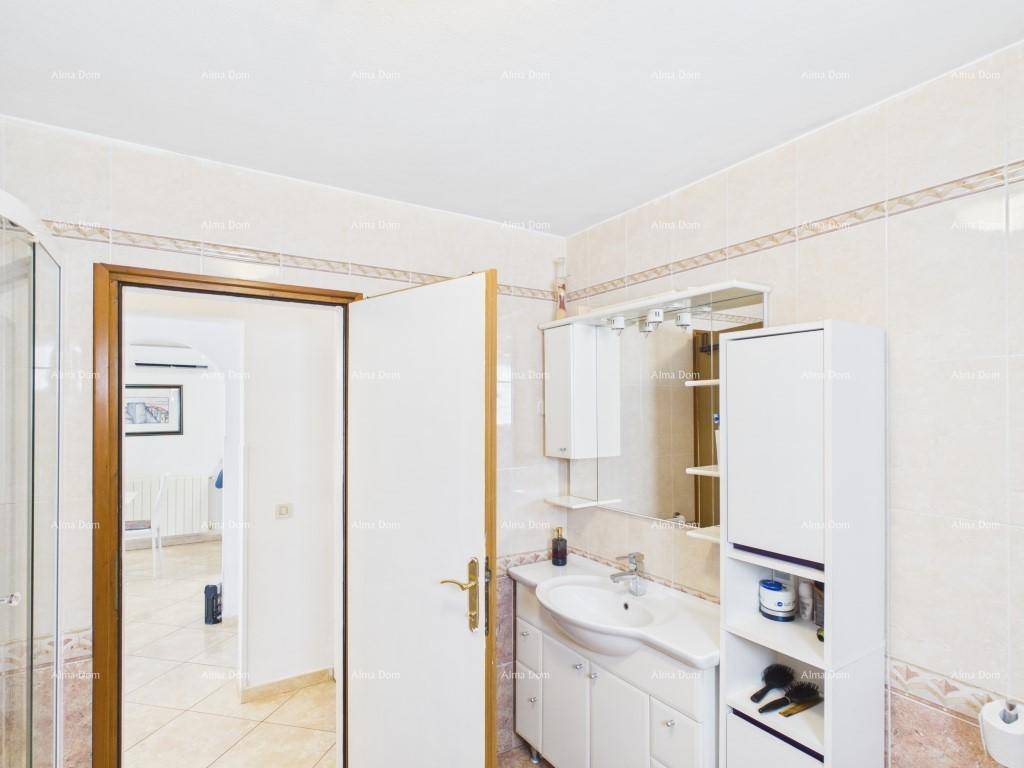 Helles Badezimmer mit Waschbecken, Spiegelschrank und weißen Fliesen, bietet direkten Zugang zu einem anderen Raum.
