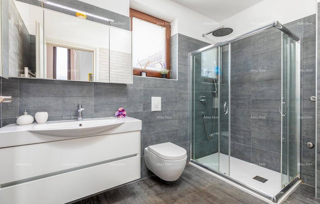 Helles Badezimmer mit grauen Fliesen, modernem Waschtisch, Spiegelschrank und großer Duschkabine.