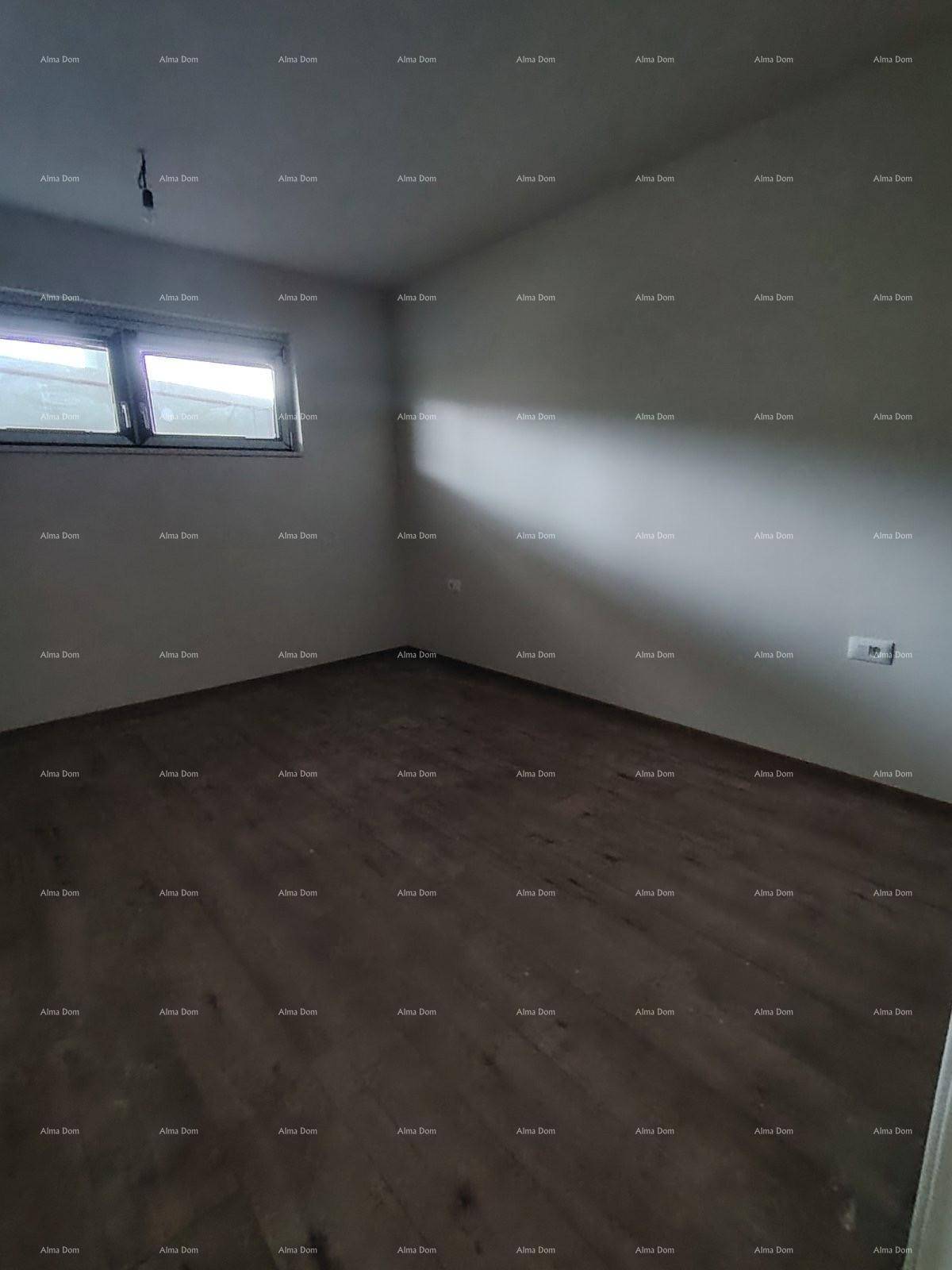 Leerer Raum mit Laminatboden und einem Fenster, das Tageslicht hereinlässt.