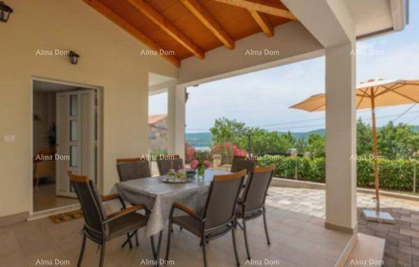 Gemütliche überdachte Terrasse mit Esstisch und Zugang zum Haus, umgeben von grüner Landschaft.
