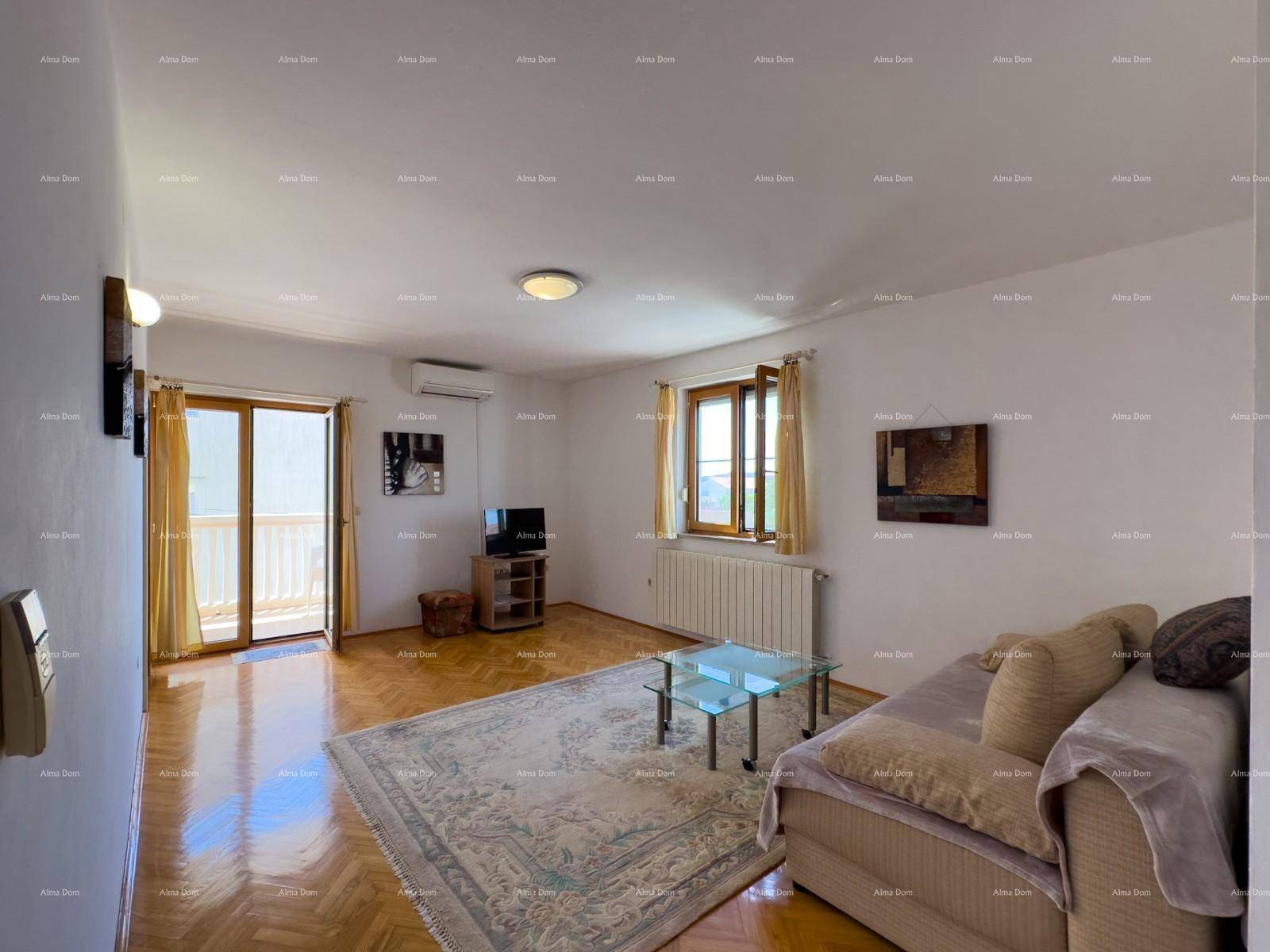 Helles Wohnzimmer mit Sofa, Couchtisch, Fernseher und Zugang zum Balkon.
