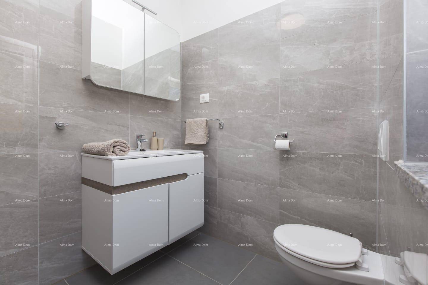 Helles Badezimmer mit modernen grauen Fliesen, schwebendem Waschtisch und Wand-WC.