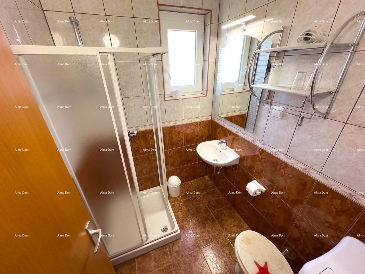 Funktionales Badezimmer mit Duschkabine, Waschbecken, WC und Fenster.