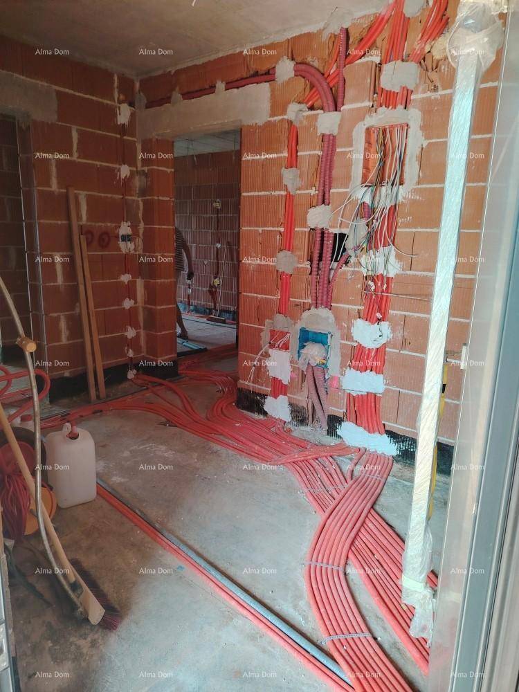 Innenraum im Rohbau mit sichtbaren Ziegelwänden und umfangreichen Elektroinstallationen auf dem Boden.