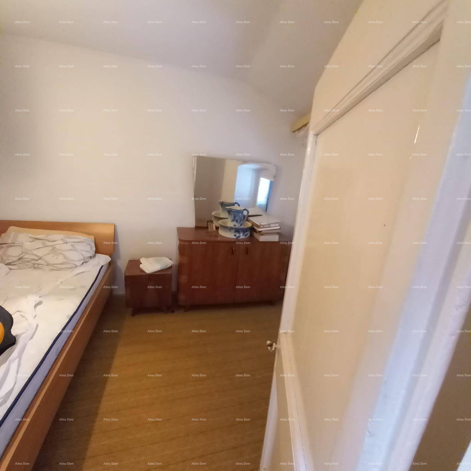 Schlafzimmer mit Holzboden, Bett, Kommode und einem Spiegel.