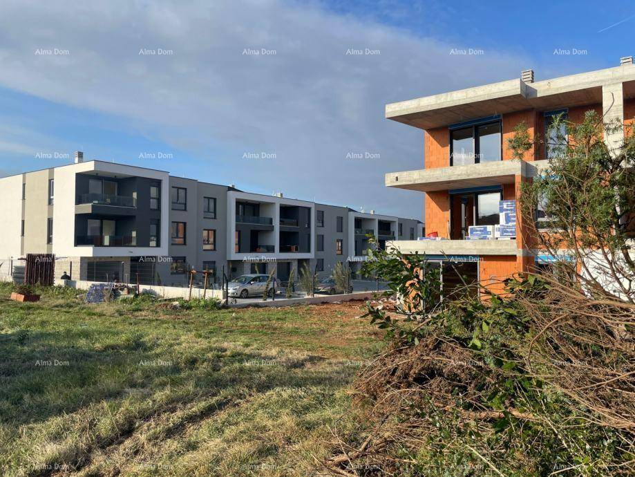 Moderne Wohngebäude im Hintergrund und ein im Bau befindliches Gebäude im Vordergrund mit Grünfläche.