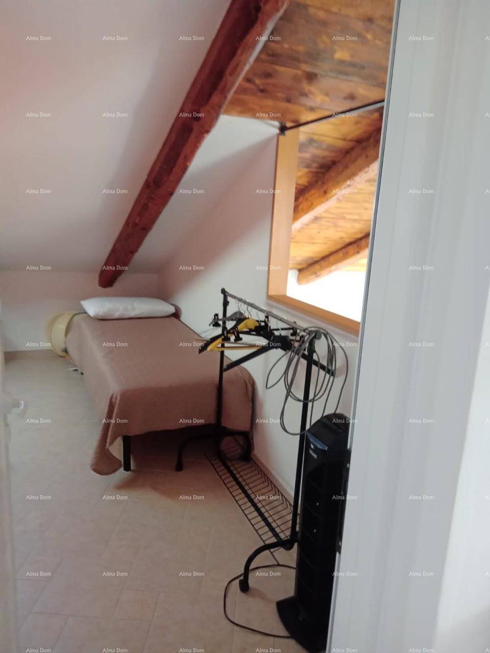 Gemütliches Schlafzimmer im Dachgeschoss mit Holzbalken, Dachschräge und Fenster.