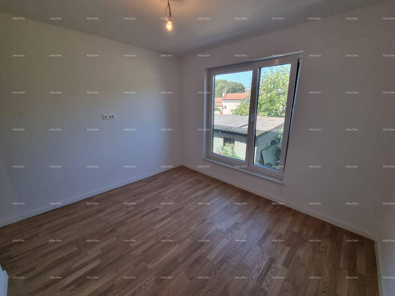 Helles Schlafzimmer mit Holzparkett und Fenster, das einen Blick auf die umliegenden Häuser und Bäume bietet.