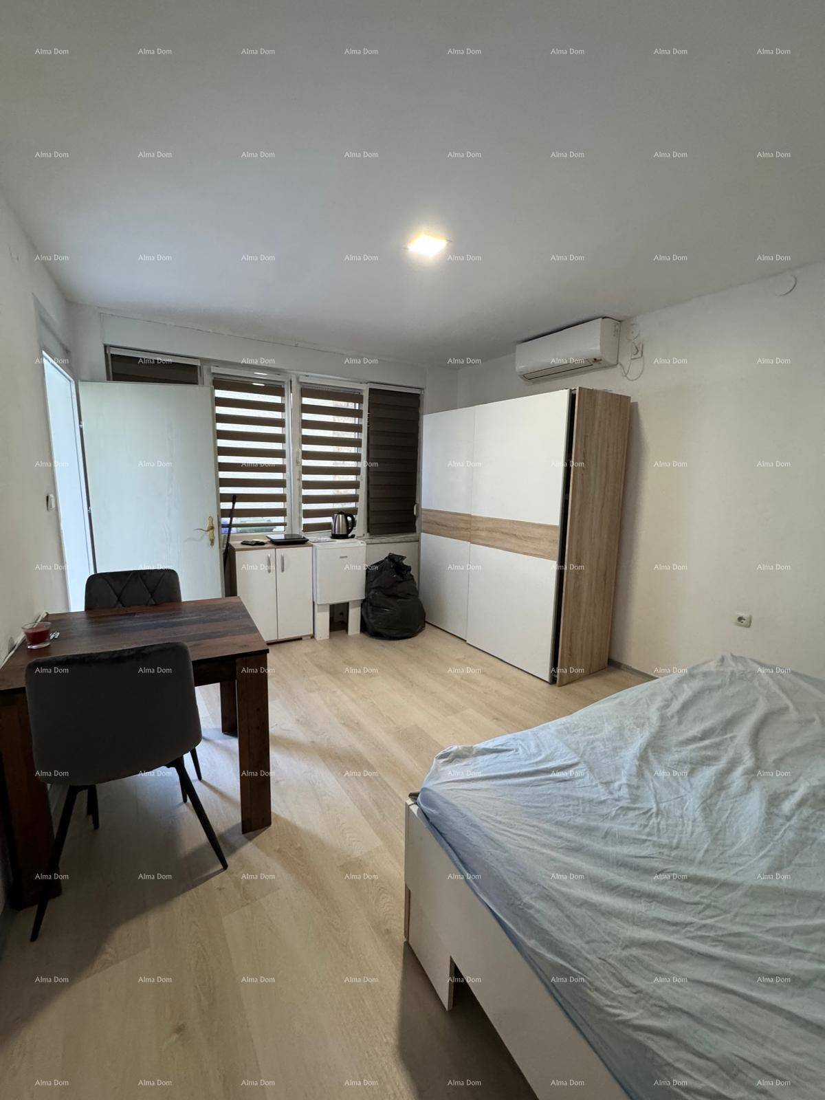 Schlafzimmer mit Doppelbett, Esstisch und Kleiderschrank, mit hellem Laminatboden.