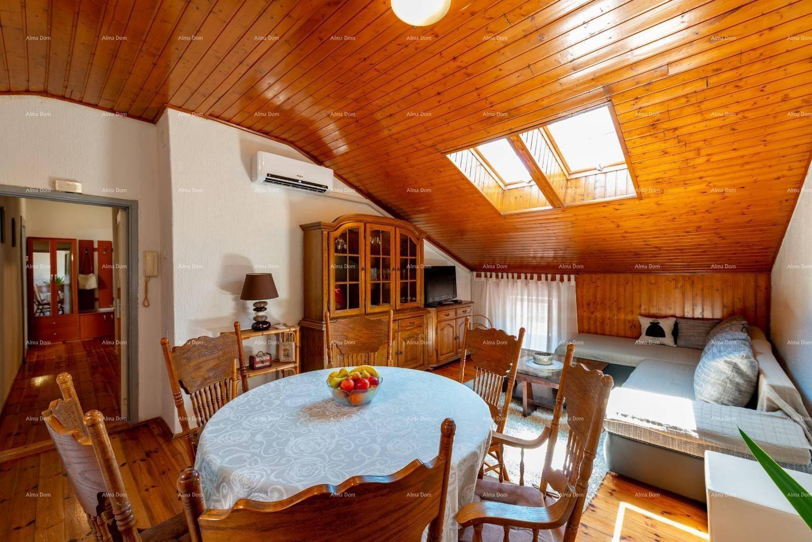 Geräumiger Wohn- und Essbereich im Dachgeschoss mit Holzboden, Esstisch und Sofa.