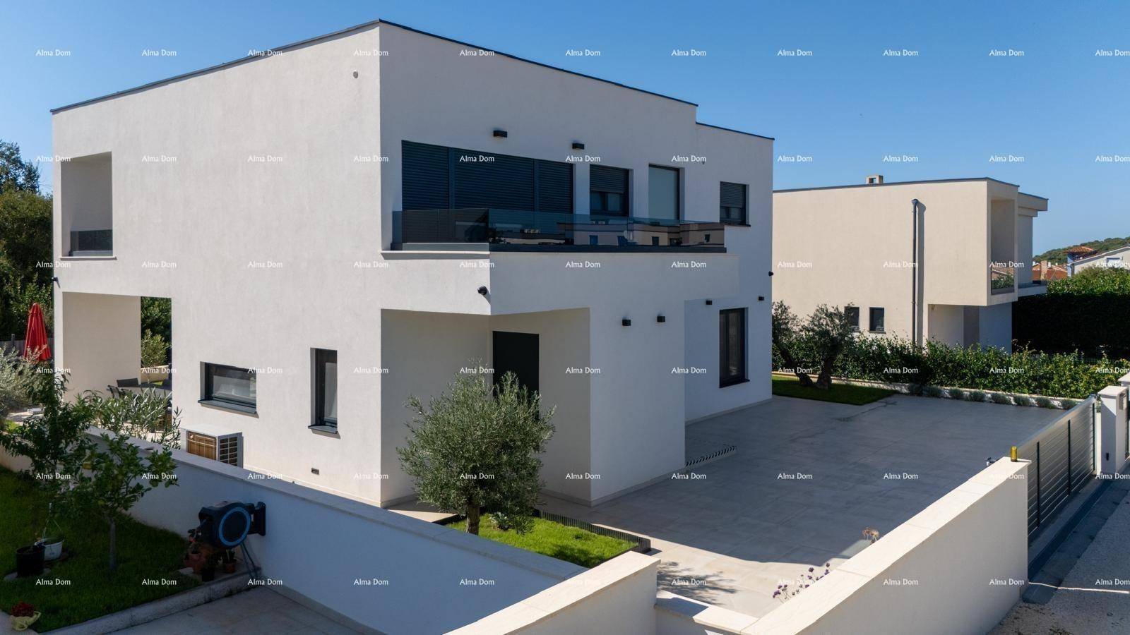 Moderne weiße Villa mit großen Fenstern, Balkon und gepflegtem Vorgarten.