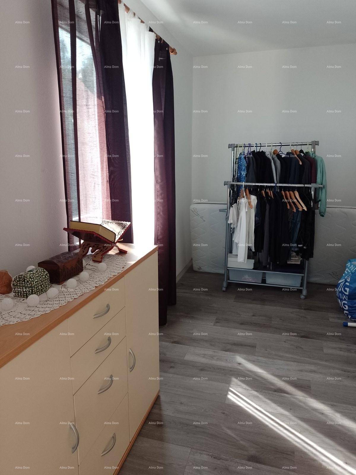 Zimmer mit Laminatboden, Kleiderstange und Schrank, gut beleuchtet durch ein Fenster.