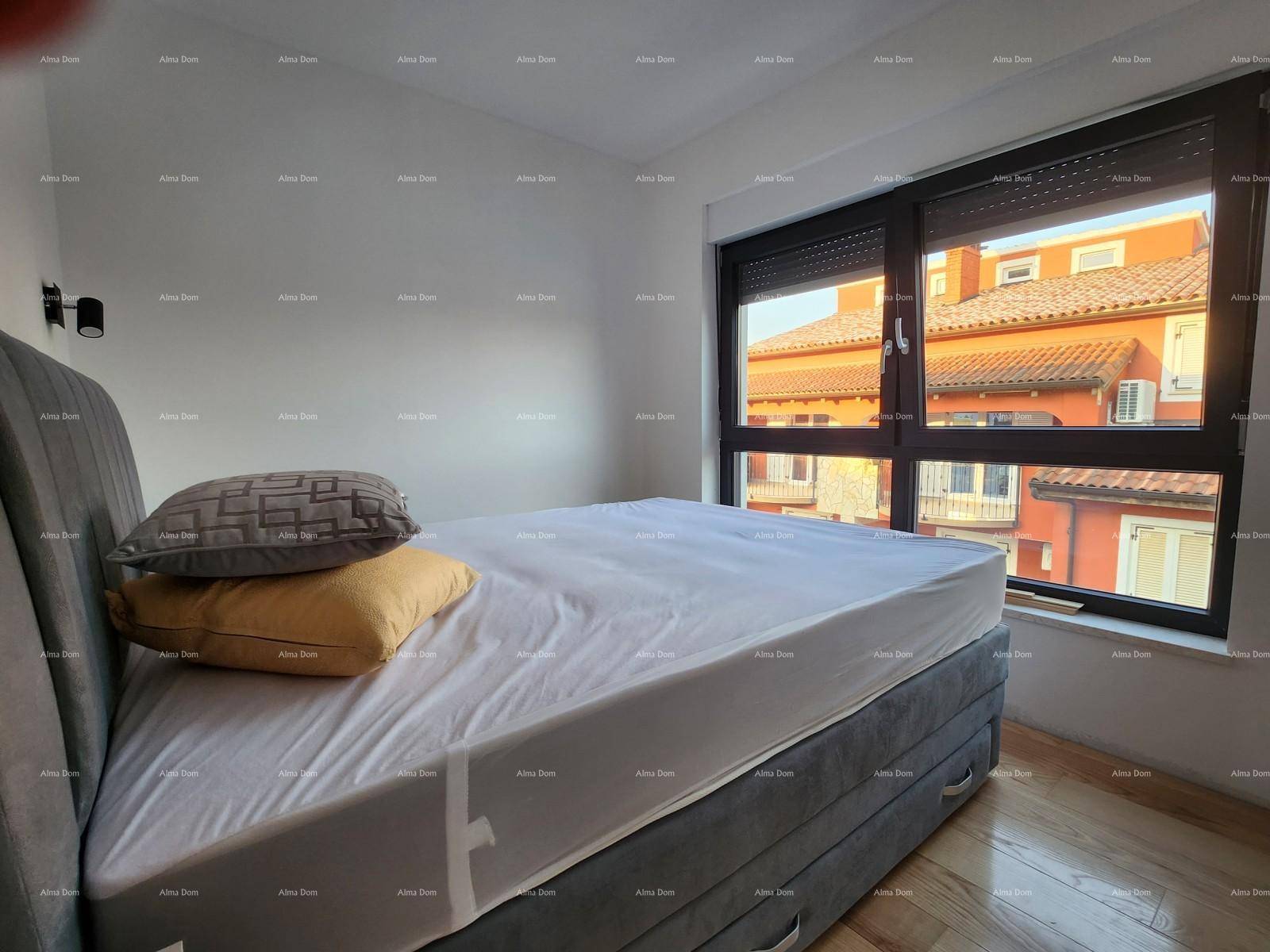 Helles Schlafzimmer mit großem Fenster, Holzboden und Blick auf die umliegenden Gebäude.