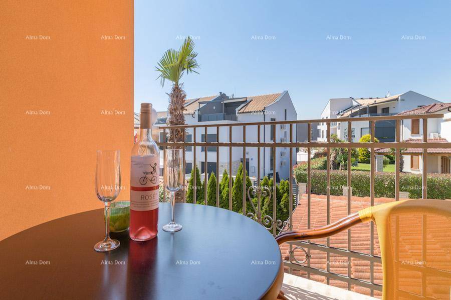 Balkon mit Tisch und Weingläsern, bietet einen Blick auf die umliegenden Gebäude und viel Grün.