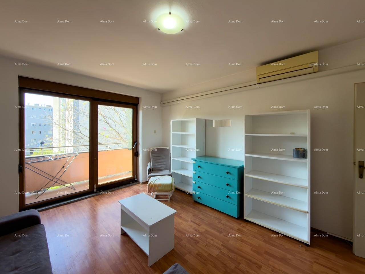 Wohnzimmer mit Holzfußboden, Klimaanlage und großen Fenstern zum Balkon.