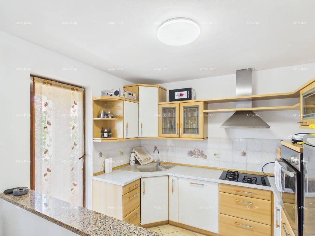Funktionale Küche mit hellen Holz- und weißen Schränken, Kochfeld, Backofen und Dunstabzugshaube.