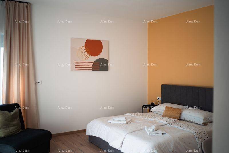 Schlafzimmer mit Doppelbett, kleinem Sofa und großem Fenster, das viel Tageslicht hereinlässt.