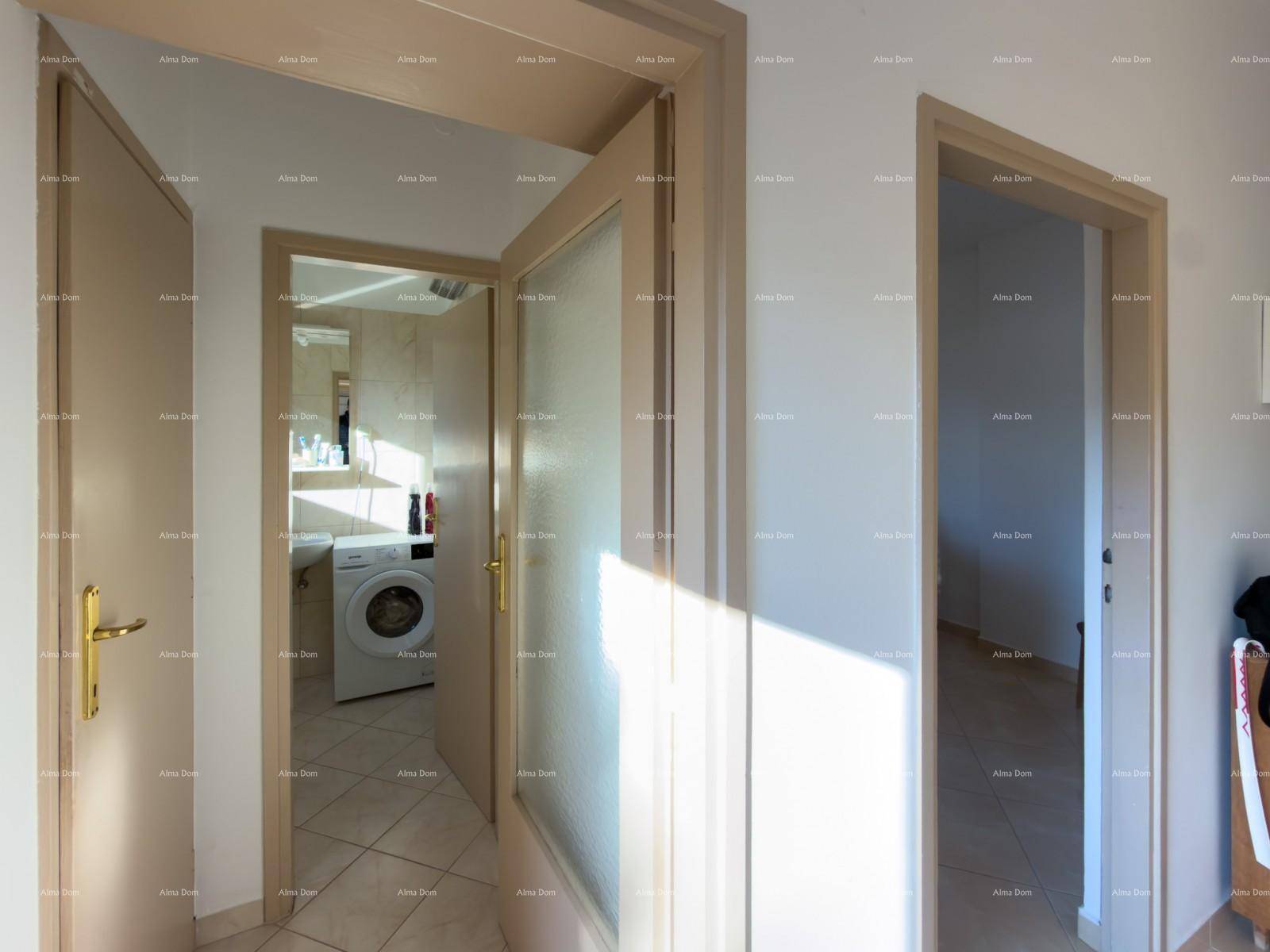 Blick vom Flur in ein Badezimmer mit Waschmaschine und Fliesenboden.