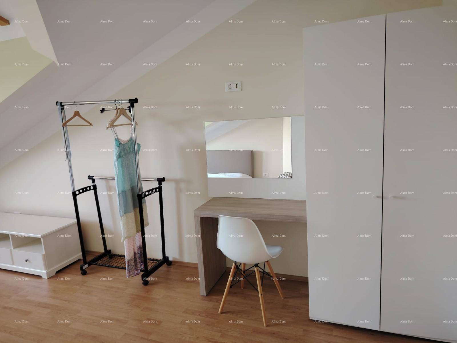 Teilansicht des Schlafzimmers mit modernem Kleiderschrank, Schreibtisch und Spiegel im Dachgeschoss.