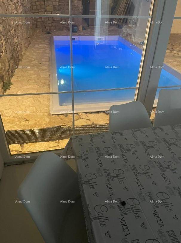 Innenansicht mit Blick auf den beleuchteten Pool durch große Fenster.