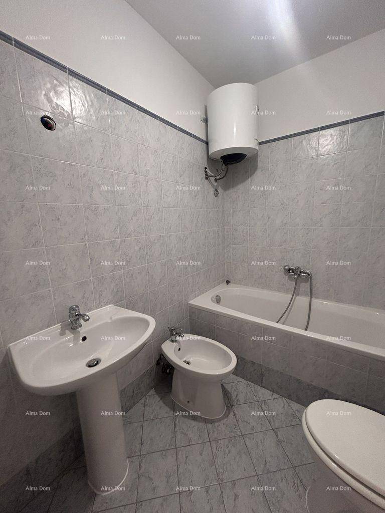 Badezimmer mit Badewanne, Bidet und hellen Fliesen, ausgestattet mit einem Warmwasserboiler.